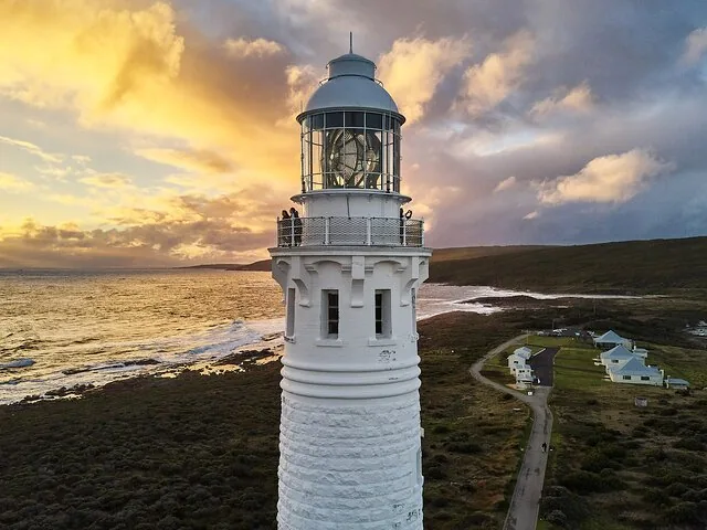 Close-up aerial view of Cape Leeuwin Lighthouse against a dramatic sunset sky.