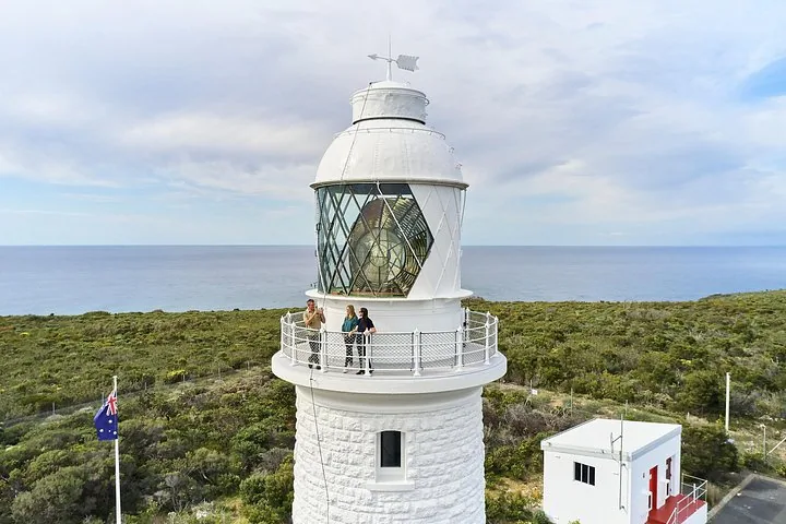 Close-up of the lighthouse lantern room with people standing on the balcony.